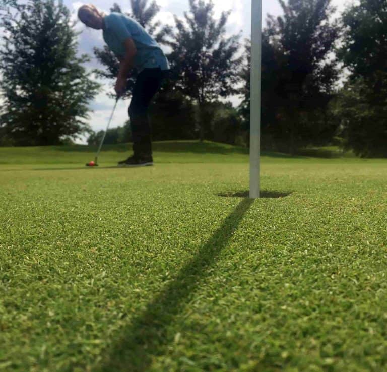Een man golft op een groene baan.